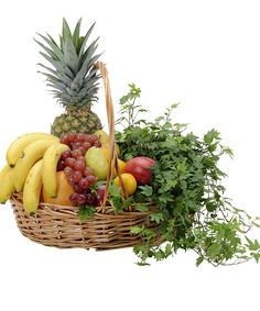 a wicker basket filled with lots of different types of fruit next to greenery