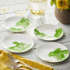 four plates with green painted rabbits on them