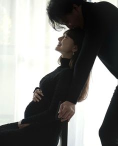 a pregnant woman leaning on the back of a man