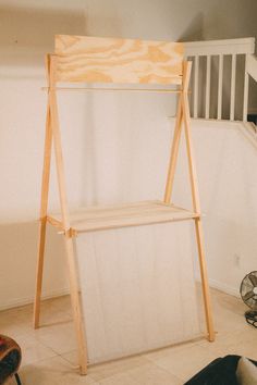 a wooden shelf sitting in the middle of a living room next to a stair case