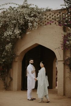 a man and woman standing in front of an archway