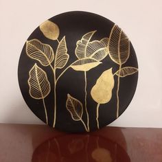 a black and gold plate with leaves on it