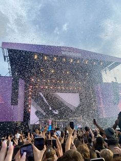 people are taking pictures with their cell phones at an outdoor concert