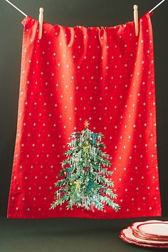 a christmas tree on a red cloth hanging from a clothes line next to two plates