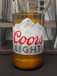 a bottle of beer sitting on top of a counter next to metal utensils