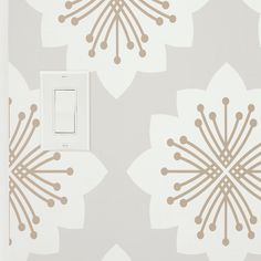 a light switch sitting on top of a wall next to a white and beige flower pattern