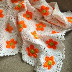 a crocheted blanket with orange flowers on it