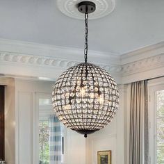 a chandelier hanging from the ceiling in a dining room with white walls and windows