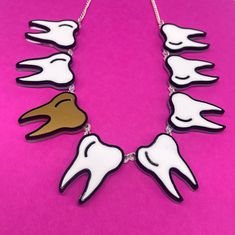 Tooth 🦷 fairy necklace is a fun, quirky accessory to pair with a any outfit. The necklace is made from white, gold and black gloss acrylic layered on a clear background. The teeth are linked together using jump rings and is linked to a curb chain with a lobster claw clasp.  Just leave a note 📝 at checkout with the word or name you would like made. If you have any questions drop us a line!💌 We are more than happy to help😁 To clean your necklace you can simply wipe with a glasses cloth or soft cloth to remove finger marks. Acrylic is a fragile material so please store in a jewellery box to prevent damage.  As ever for safety please keep away from small children. White Novelty Jewelry For Party, Novelty White Jewelry For Party, White Novelty Party Jewelry, Novelty White Handmade Necklace, Handmade White Novelty Necklace, Plastic Jewellery, Laser Cut Jewelry, Fairy Necklace, Clear Background