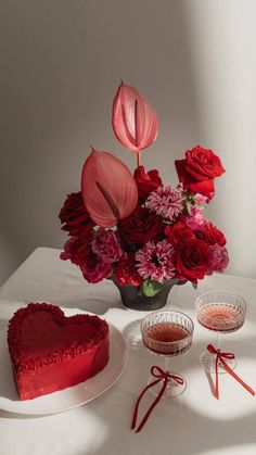 a heart shaped cake sitting on top of a table next to a vase filled with flowers