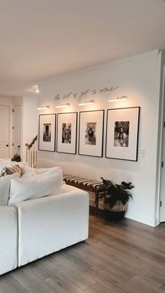 a large white couch sitting in a living room next to a wall with pictures on it