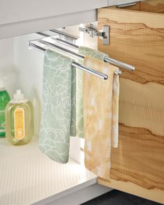 towels are hanging on the rail in front of the cabinet door, and soap is next to it