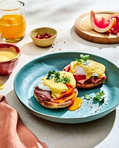 two sandwiches are sitting on a blue plate with orange juice and watermelon in the background