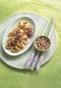 a white plate topped with food next to chopsticks and a bowl filled with vegetables