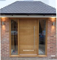 a modern wooden door with glass panels on the side of a brick building in england