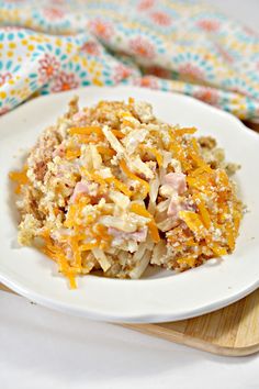 a white plate topped with macaroni and cheese covered in sauce on top of a wooden cutting board