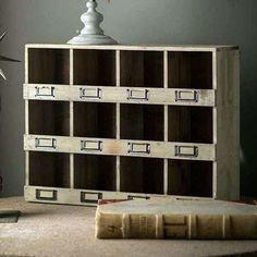 an old bookcase is sitting on a table next to a vase with flowers in it