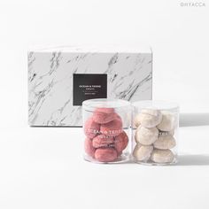 two clear jars filled with candy next to a marbled box and white wallpaper