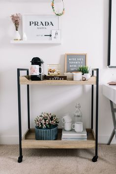 a shelf with flowers, coffee cups and other items on it next to a desk