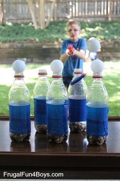 several bottles of water are lined up in front of a man holding an object with one hand