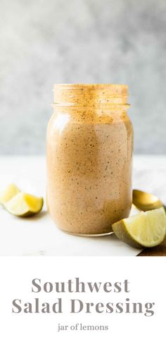 a jar filled with salad dressing next to sliced lemons and lime wedges on the side