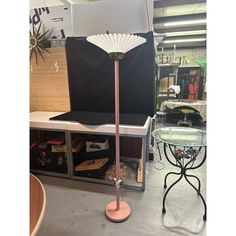 a pink table lamp sitting on top of a metal stand next to a glass table