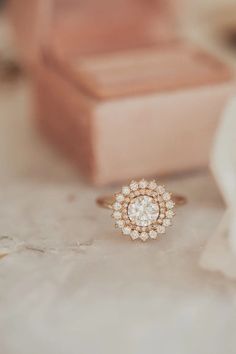 a diamond ring sitting on top of a table next to a piece of paper and a box