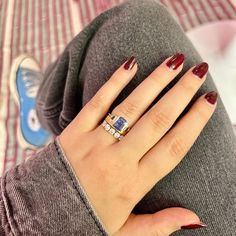 a woman's hand with red and white nail polish holding a ring on her finger