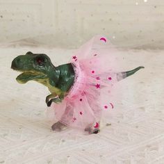 a toy dinosaur in a pink tutu skirt