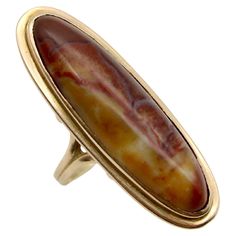 This stunning 18k gold and agate cabochon ring is from the Victorian era. The striking bezel set agate is an elongated oval shape, which graces the hand elegantly. The agate contains a marbled array of beautiful earth tones ranging in color from cream to caramel to burnt sienna with red undertones. The stone is flanked by open work details in the 18k gold band. The agate is a generous size of 35 x 10 mm. The ring weighs approximately 6 grams. It is unmarked, but tests to be 18k gold. Ring size 7 Elongated Oval, The Victorian Era, Burnt Sienna, Agate Cabochon, Cabochon Ring, Jewelry Lookbook, Oval Cabochon, Gold Band, Antique Rings