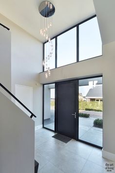 a modern entry way with glass doors and chandelier