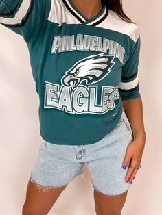 This Vintage 1997 Philadelphia Eagles Shirt is epic. The top portion of this shirt features a jersey material with a t-shirt body. how to style: This is so cute paired with a simple denim short and boots. care: 100%POLYESTER, hand wash cold, line dry size: model is wearing size small 90s Streetwear Tops For Fall, 90s Inspired Blue Tops With Letter Print, 90s Inspired Graphic Print Tops For Fall, 90s Inspired Graphic Print Fall Tops, Trendy Crew Neck Top For Game Day, Retro Fan Merchandise Tops For Fall, Spring Game Day Top With Text Print, 90s Inspired Crew Neck Top For Fall, 90s Relaxed Fit Top For Fan Merchandise