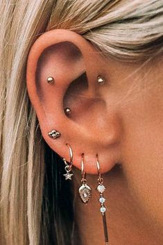 a close up of a person wearing ear cuffs and piercings on their left side