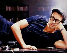 a man laying on top of a table next to a book shelf