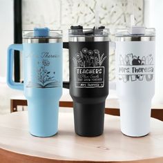 three travel mugs sitting next to each other on a table