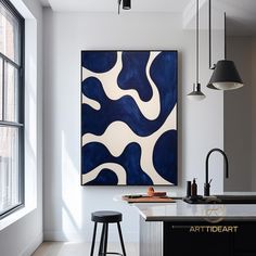 an abstract painting hangs on the wall above a kitchen island in front of a window