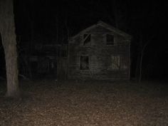 an old house in the woods at night with no one around it or on the ground