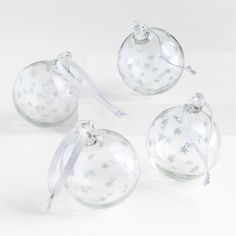 four glass ornaments with white snowflakes on them