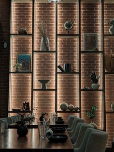 a dining room table and chairs in front of a brick wall with vases on it