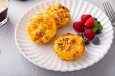 three breakfast muffins on a white plate with berries and raspberries