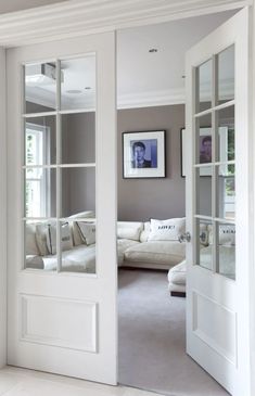 an open door leading to a living room with white couches and pillows on the floor