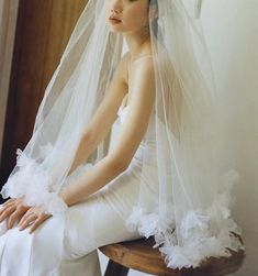 a woman sitting on top of a wooden chair wearing a wedding veil