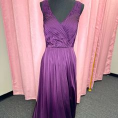 a purple dress is displayed on a mannequin in front of pink drapes