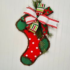 a christmas stocking hanging on the side of a white wall with green and red decorations