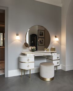 a dressing table with a mirror and stool next to it in a room that has white walls