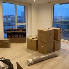 boxes are stacked on top of each other in an empty room with large windows overlooking the city