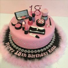 a birthday cake with pink frosting and black trimmings, including makeup items