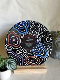 a black and white plate sitting on top of a wooden stand next to a potted plant