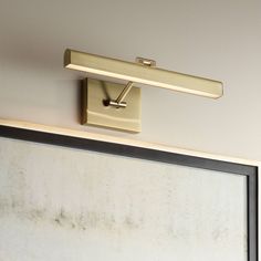 a light that is on the side of a wall next to a framed piece of paper