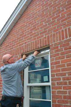 a man is painting the window of a brick building